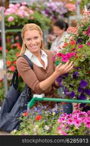 Smiling woman shopping for colorful flowers in garden center
