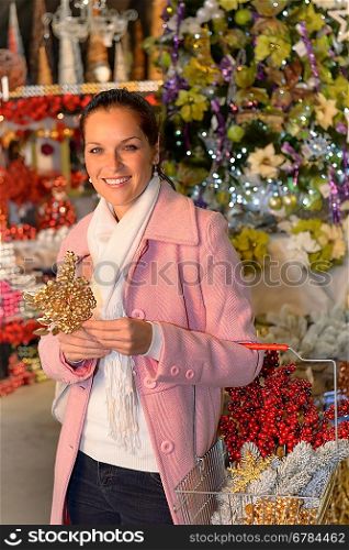 Smiling woman shopping Xmas decorations with shopping basket