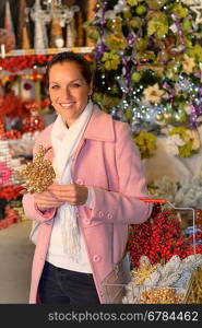 Smiling woman shopping Xmas decorations with shopping basket