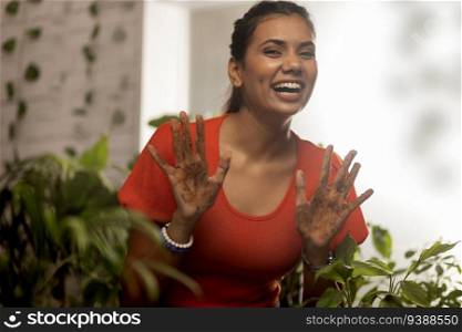 Smiling woman showing her muddy hands in front of camera during gardening