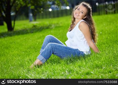 Smiling woman sits on a summer lawn