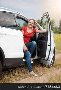 Smiling woman sitting in car at the field
