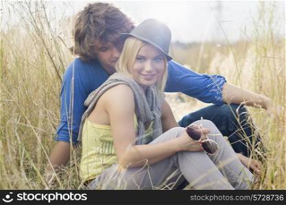 Smiling woman sitting with loving man in field