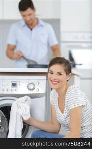 smiling woman taking cloths from washing machine