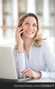 Smiling woman talking in the phone in the office