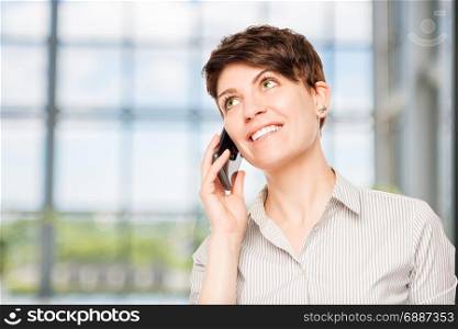 smiling woman talking on a mobile phone in the office
