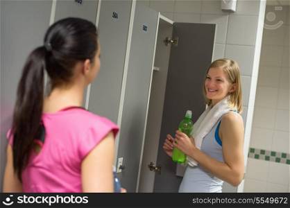 Smiling woman talking with friend in changing room at healthclub