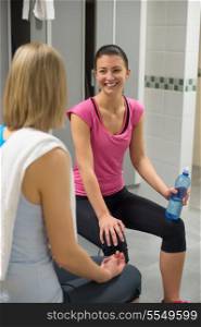 Smiling woman talking with friend in locker room at gym