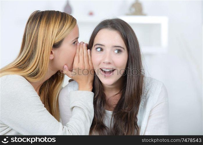 smiling woman telling secret to friend