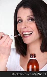 Smiling woman treating her bronchitis with syrup