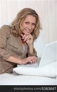 Smiling woman using her laptop on a white sofa