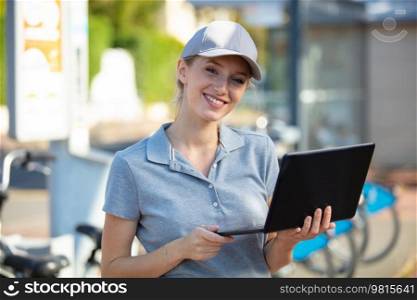 smiling woman using laptop in the street
