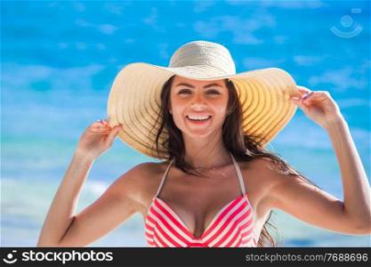 Smiling Woman wearing bikini swimwear and sunhat on sea beach. Woman wearing sunhat on beach