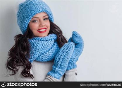 Smiling woman wearing blue winter hat, scarf and mittens