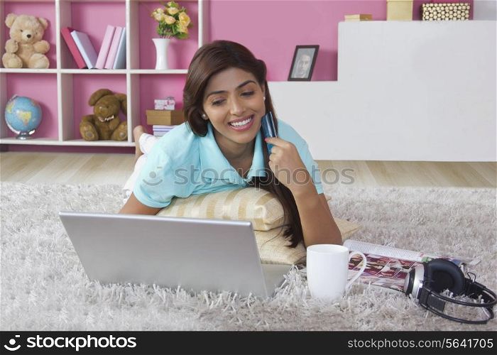 Smiling woman with credit card shopping online at home