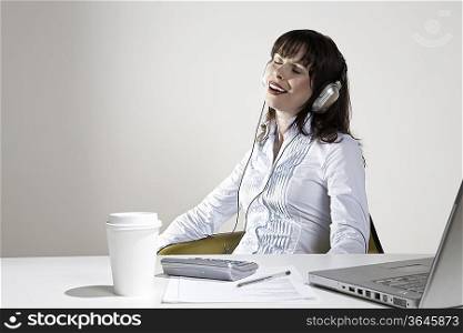 Smiling woman with earphones relaxing at desk