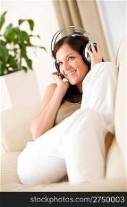 Smiling woman with headphones listen to music, plant in background