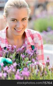 Smiling woman with purple flower working in garden center