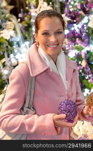 Smiling woman with shiny Christmas balls at wintertime