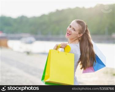 Smiling woman with shopping bags walking embankment
