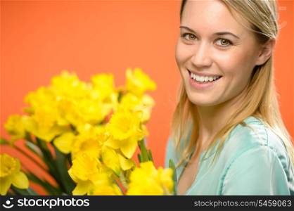 Smiling woman with spring yellow narcissus flowers on orange background