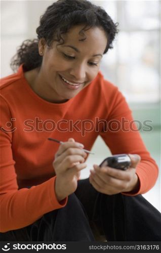 Smiling woman with stylus looking at mobile phone