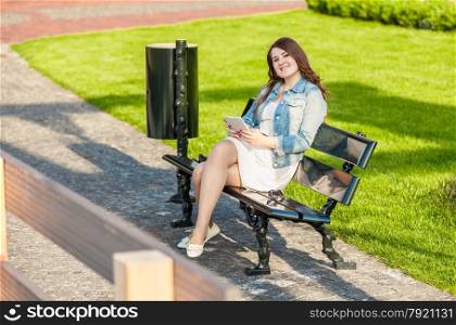 Smiling woman with tablet on bench at park