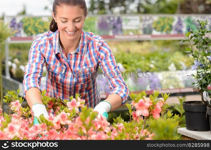 Smiling woman working with potted flowers at garden center