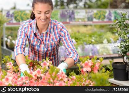 Smiling woman working with potted flowers at garden center