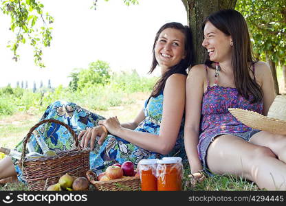 Smiling women picnicking in orchard