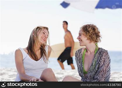 Smiling women talking on beach