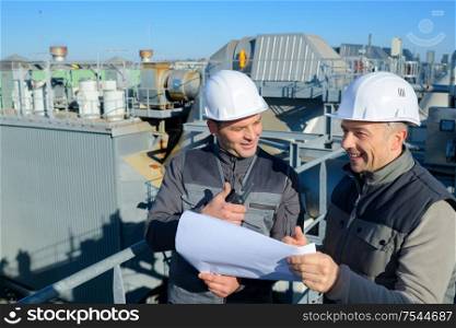 smiling workmen holding plans and giving thumbs up