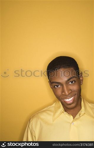 Smiling young African-American man wearing yellow clothing on yellow background.
