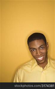 Smiling young African-American man wearing yellow clothing on yellow background.