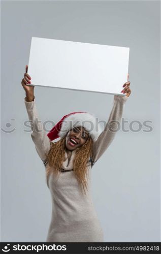 Smiling young african woman in Santa Claus hat holding sign overhead