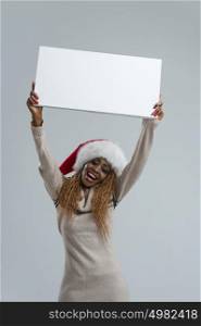 Smiling young african woman in Santa Claus hat holding sign overhead