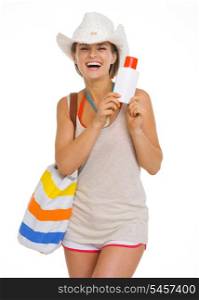 Smiling young beach woman in hat holding sun screen creme