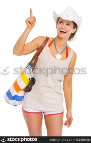 Smiling young beach woman in hat pointing on copy space