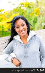 Smiling young black woman outside in casual hoodie on windy day