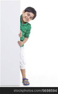 Smiling young boy peeking through billboard
