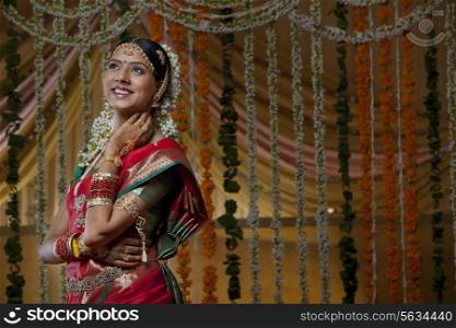 Smiling young bride looking away with flower decoration in background