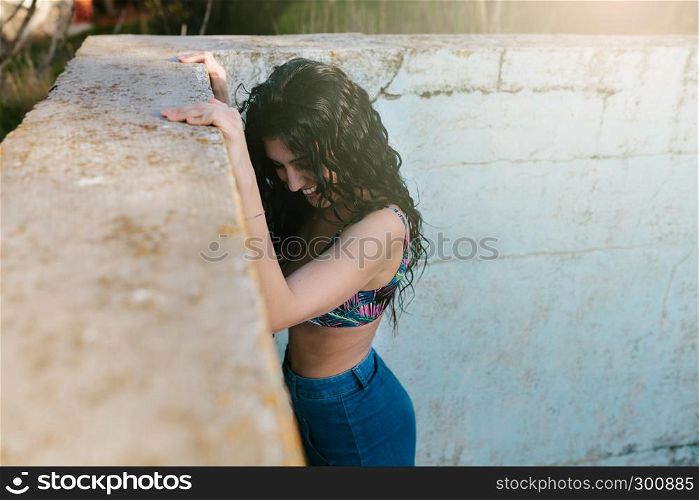 Smiling young brunette woman with bikini in an old empty pool