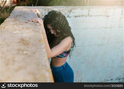 Smiling young brunette woman with bikini in an old empty pool
