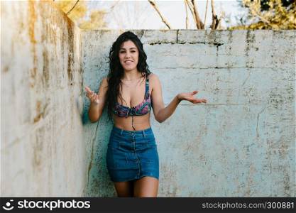 Smiling young brunette woman with bikini in an old empty pool with surprise expression