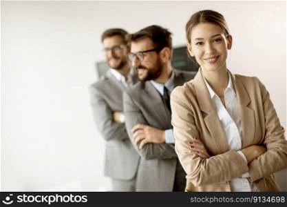 Smiling young business woman standing with group of corporate colleagues in a row together at the office