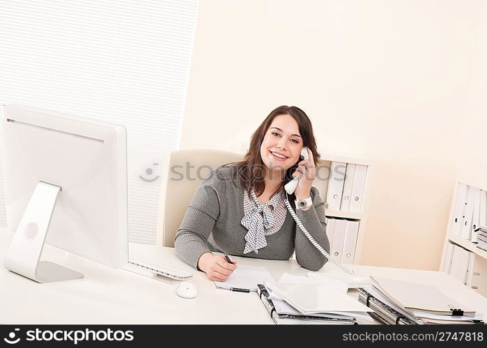 Smiling young business woman working on the phone at office