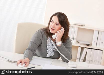 Smiling young business woman working on the phone at office