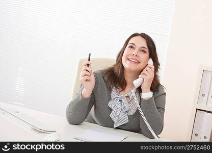 Smiling young business woman working on the phone at office