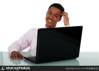 Smiling young businessman at a laptop