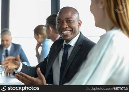 Smiling young businessman discussing with female colleague in board room